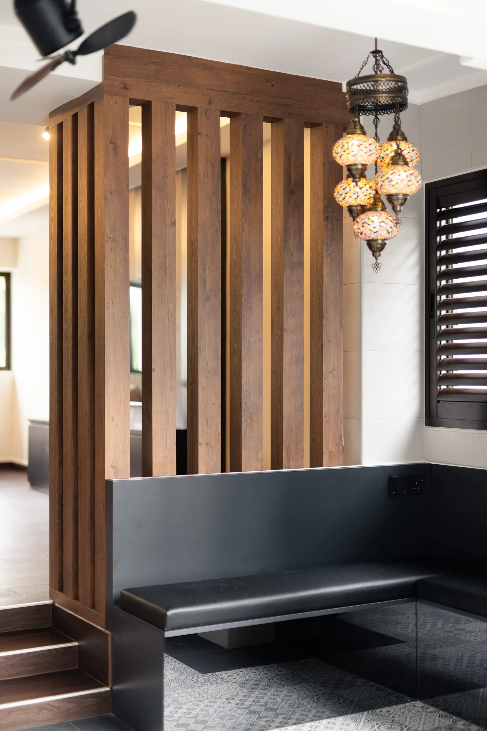 A timber screen entryway with a Moroccan lantern and black bench