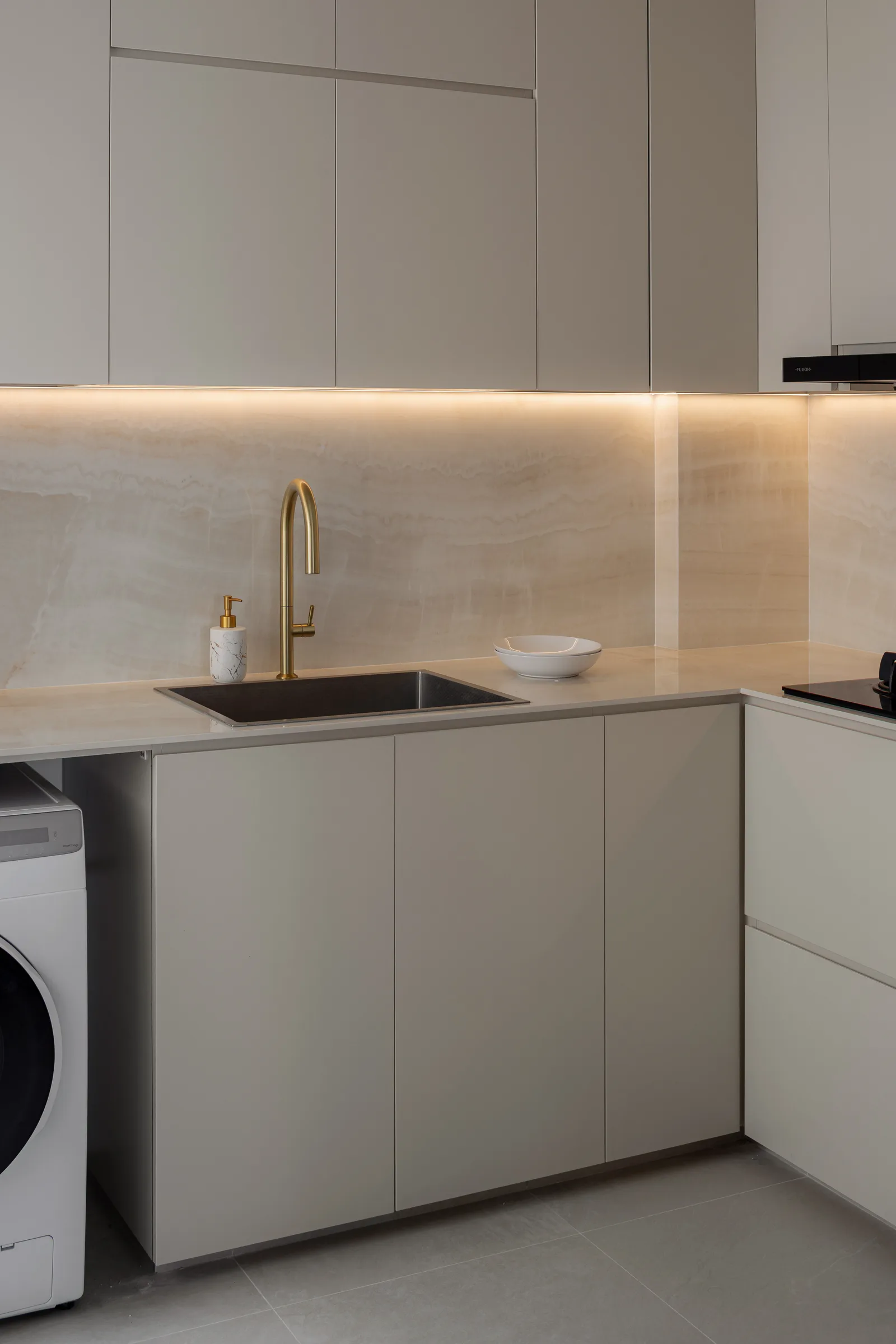 A bright cream kitchen with brass tapware and under-cabinet lighting