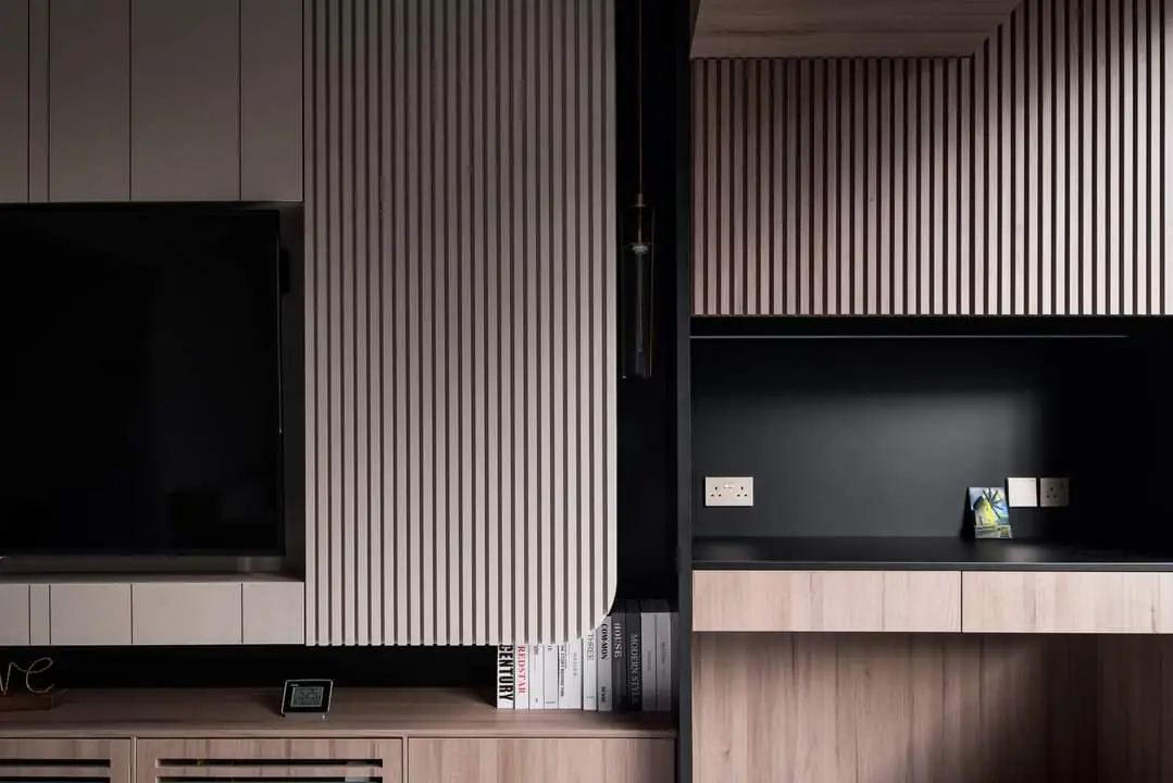 A fluted-oak feature wall wrapping a recessed TV and a black stone study nook